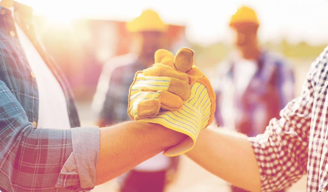 Se muestra a dos compañeros de trabajo dandose la mano en un entorno laboral