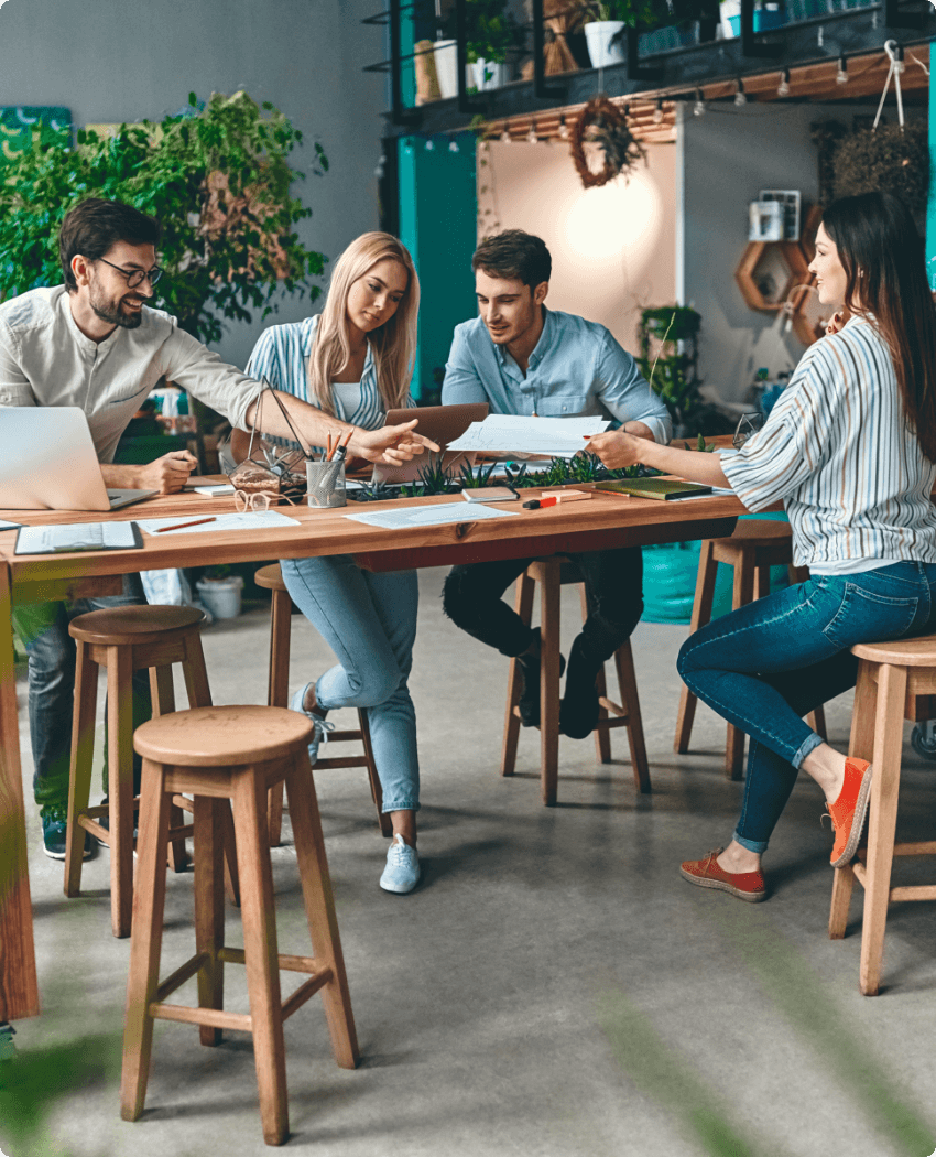 Se muestra un equipo de trabajo en una oficina llena de plantas en un ambiente amigable